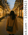 Back view of a woman walking through the night illuminations 130099423