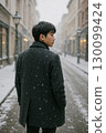 Back view of a man walking through a snowy city 130099424