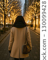 Back view of a woman walking along an illuminated avenue 130099428