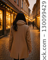 Back view of a woman walking through an illuminated street 130099429
