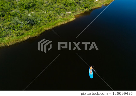 Happy mother with child have a fun on stand up paddle SUP board in sea lagoon. Healthy lifestyle. Recreational water sport, SUP tour in adventure camp on family summer beach vacation 130099455