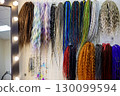 A vibrant assortment of hair extensions in various styles and colors hangs neatly on display, showcasing trends and creativity in hair fashion within a stylish salon. 130099594