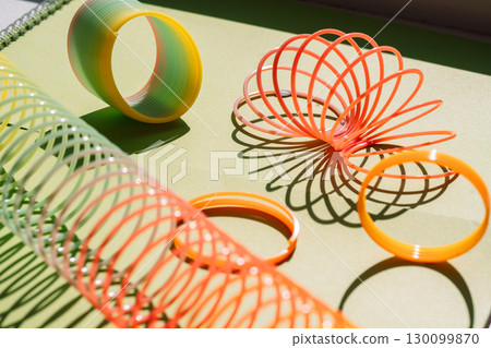 Colorful slinky toys on green surface 130099870