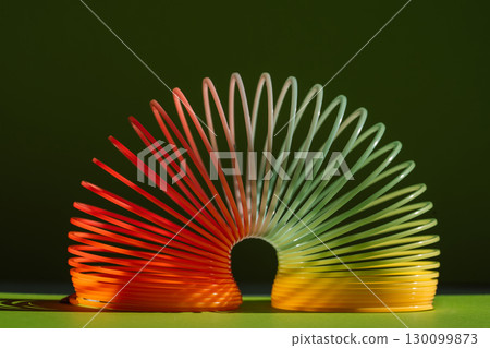 Colorful plastic spring toy on green background Colorful plastic spring toy on green background 130099873