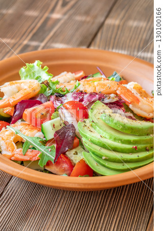 Fresh prawn avocado salad cherry tomatoes wooden table citrus dressing 130100166