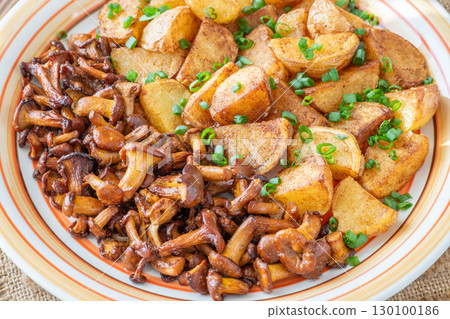 Fried potatoes chanterelle mushrooms seasoned paprika rustic wooden table plate Fried potatoes chanterelle mushrooms seasoned paprika rustic wooden table plate 130100186
