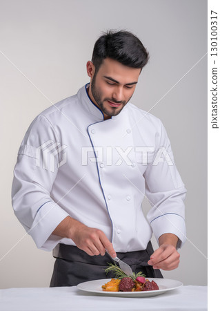 A chef dressed in a white uniform garnishes food with fresh ingredients 130100317