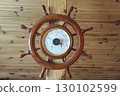 nautical ship wheel barometer with thermometer and hygrometer, crafted in wood on the woodan wall background. Perfect marine decor for sailors, sea lovers, and coastal home interiors 130102599