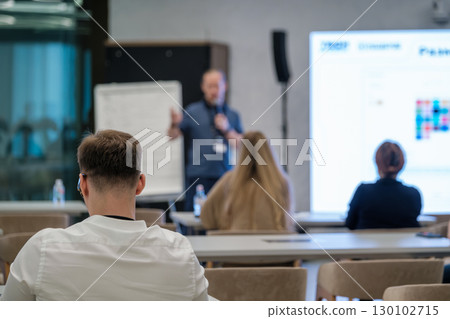Team attending an educational business presentation in a modern meeting room 130102715