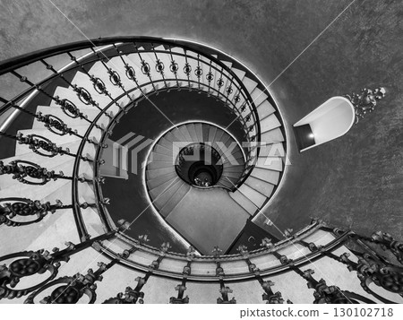 Spiral staircase in classic architecture with ornamental railing design in black and white Spiral staircase in classic architecture with ornamental railing design in black and white 130102718