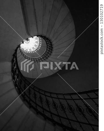 Black and white spiral staircase viewed from below with intricate railing design Black and white spiral staircase viewed from below with intricate railing design 130102719