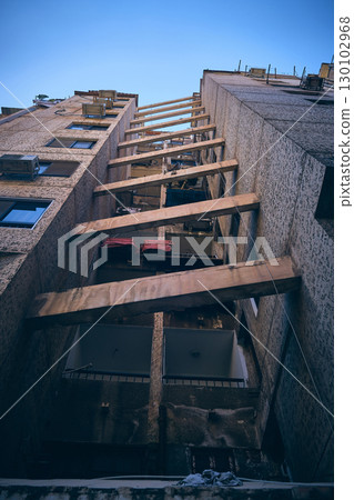 Urban alley with high-rise buildings and connecting wooden beams 130102968