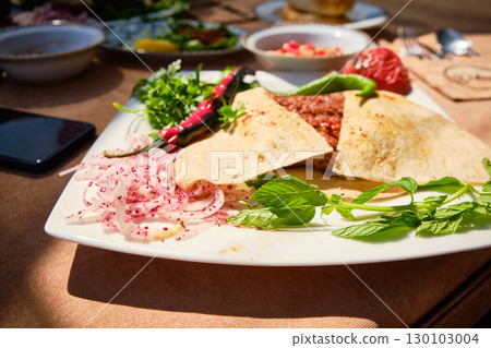Traditional Middle Eastern Meat Flatbread with Fresh Herbs and Vegetables 130103004