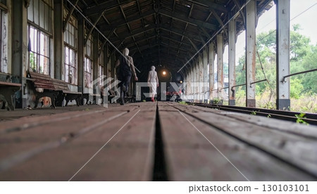 Haunted abandoned train station with ghostly figure walking alone, spooky eerie atmosphere for Halloween mystery and horror theme 130103101