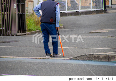 一位年長的交通管理員在停車場出口等候 一位年長的交通管理員在停車場出口等候 130103181