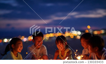 Children laughing innocently around fireworks on the beach 130103433