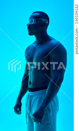 Side profile of shirtless male model in transparent futuristic visor with cyan glow 130104182