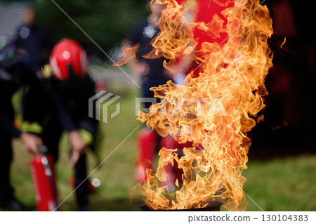 Vibrant Flame. Firefighters practice controlling an outdoor fire with extinguishers 130104383