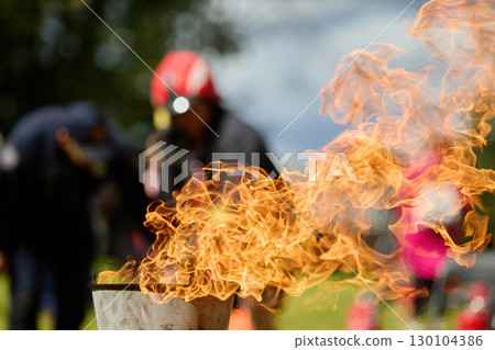 Vibrant Flame. Firefighters practice controlling an outdoor fire with extinguishers 130104386