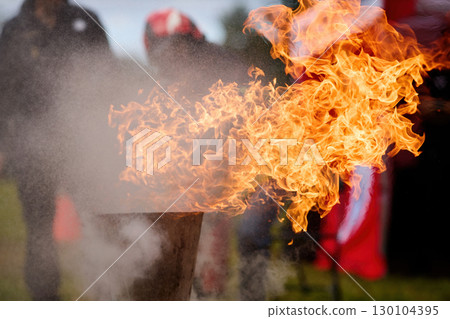 Vibrant Outdoor Flames. Firefighters practice controlling an outdoor fire with extinguishers 130104395