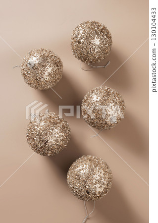 Christmas golden shiny baubles on beige background. Creative Xmas greeting card. New Year concept. Mocha Mousse. Top view. 130104433