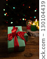 Wrapped Presents, Candles And Christmas Tree Lights On Wooden Surface 130104439