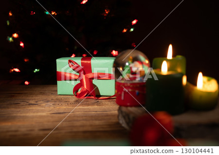 Christmas Gift, Candles, and Snow Globe on Wooden Surface During Nighttime 130104441