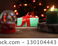Christmas Present, Lighted Candle and Snow Globe on Wood Surface 130104443