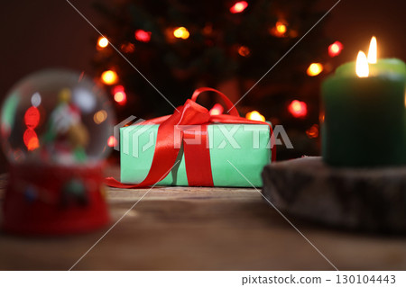 Christmas Present, Lighted Candle and Snow Globe on Wood Surface Christmas Present, Lighted Candle and Snow Globe on Wood Surface 130104443