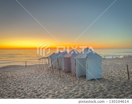 View of furadouro beach at sunset with blue and white striped beach tents. Ovar, Aveiro, Portugal 130104614