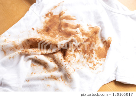 Dirty stains covering white t-shirt lying on wooden table Dirty stains covering white t-shirt lying on wooden table 130105017