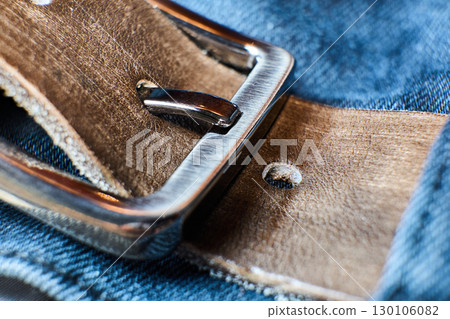 Leather belt buckle clasped on blue denim material Leather belt buckle clasped on blue denim material 130106082