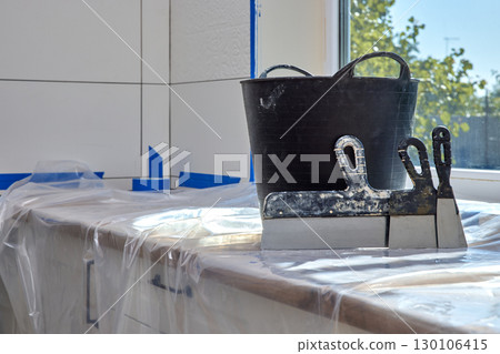 wall repair tools. Kit of putty knives and plaster bucket on kitchen countertop. renovation work wall repair tools. Kit of putty knives and plaster bucket on kitchen countertop. renovation work 130106415