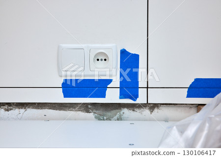 blue painters tape used for tiling kitchen walls, copy space. socket and switch on wall with tiles 130106417