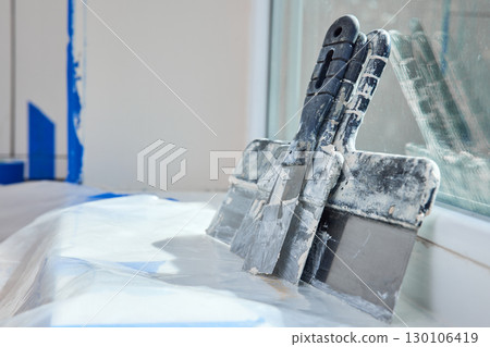 Kit of putty knives on white windowsill, copy space. Workplace. Construction tool. Kit of putty knives on white windowsill, copy space. Workplace. Construction tool. 130106419