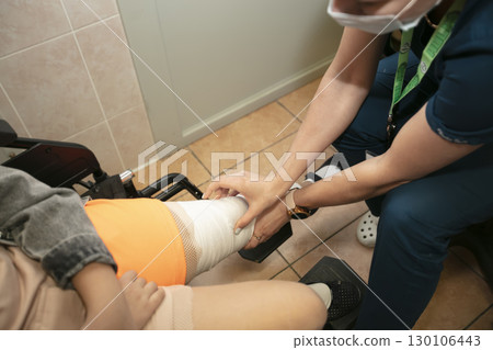The doctor touches the leg bandaged with a bandage. Fracture of the lower limbs of a person. Bone fracture treatment. Plaster is applied. Surgical department of the patient. 130106443