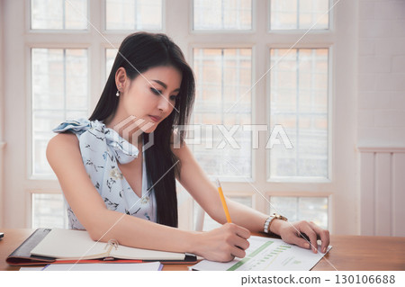 Asian woman holding pencil analysis the graph at the home office for setting challenging business goals And planning to achieve the new target. 130106688