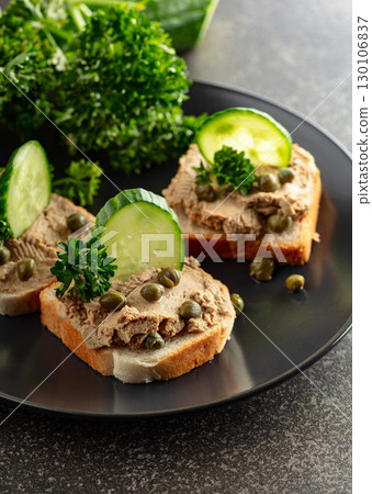 Open sandwiches with pate, fresh cucumber, capers, and parsley. 130106837