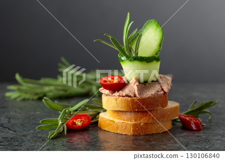 Bread slices with pate, cucumber, red pepper, and rosemary. Bread slices with pate, cucumber, red pepper, and rosemary. 130106840