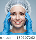 A smiling young adult woman with pre-surgical markings on her face wears a bouffant cap and blue gloves. Generative AI. 130107262