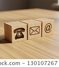 Three wooden blocks display symbols for telephone, email, and at-sign, representing various contact methods on a wooden table. Generative AI. 130107267