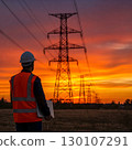 A rear-view photograph of a male engineer in a hard hat and vest holding a laptop, standing before a line of power pylons at sunset. Generative AI. 130107291