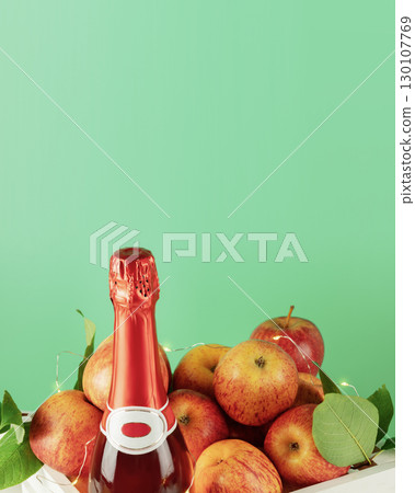 Apple wine or cider drink or fermented fruit drink. Bottle with cider and red organic apples in a white wooden box on a green background with copy space. Apple, low alcohol drink 130107769