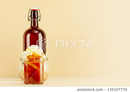 Pickled or fermented vegetables. Sauerkraut, lecho in glass jars and bottle of home made beer on light background with copy space. Home food preserving or canning. Autumn food and oktoberfest concept 130107779