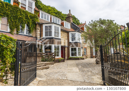 Charming English Cottage Exterior with Ivy, Bay Windows and Wrought Iron Gate Charming English Cottage Exterior with Ivy, Bay Windows and Wrought Iron Gate 130107800