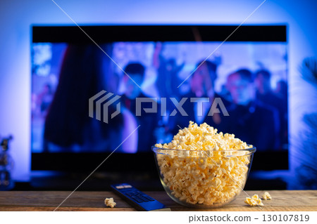 A glass bowl of popcorn and remote control in the background the TV works 130107819