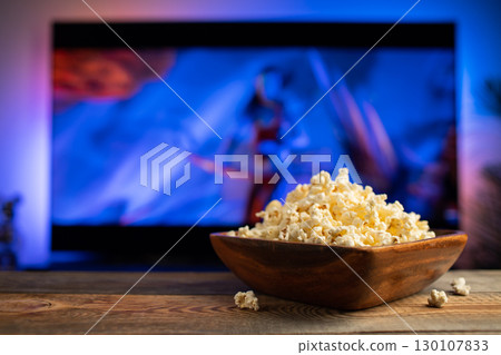 A wooden bowl of popcorn and remote control in the background the TV works 130107833