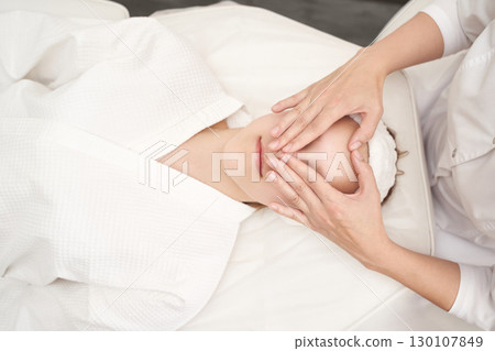 Caucasian female enjoying relaxing spa facial massage at wellness center Caucasian female enjoying relaxing spa facial massage at wellness center 130107849