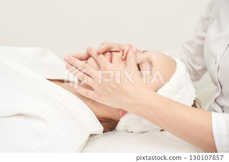 Relaxing facial treatment for young caucasian female in spa setting promoting Relaxing facial treatment for young caucasian female in spa setting promoting 130107857