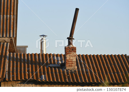The chimney on the old house. An iron pipe and a slate roof. 130107874
